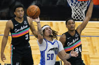 Orlando Magic guard Cole Anthony (50) takes a shot as he gets between San Antonio Spurs forward Keldon Johnson (3) and guard Devin Vassell (24) during the first half of an NBA basketball game, Monday, April 12, 2021, in Orlando, Fla. (AP Photo/John Raoux)