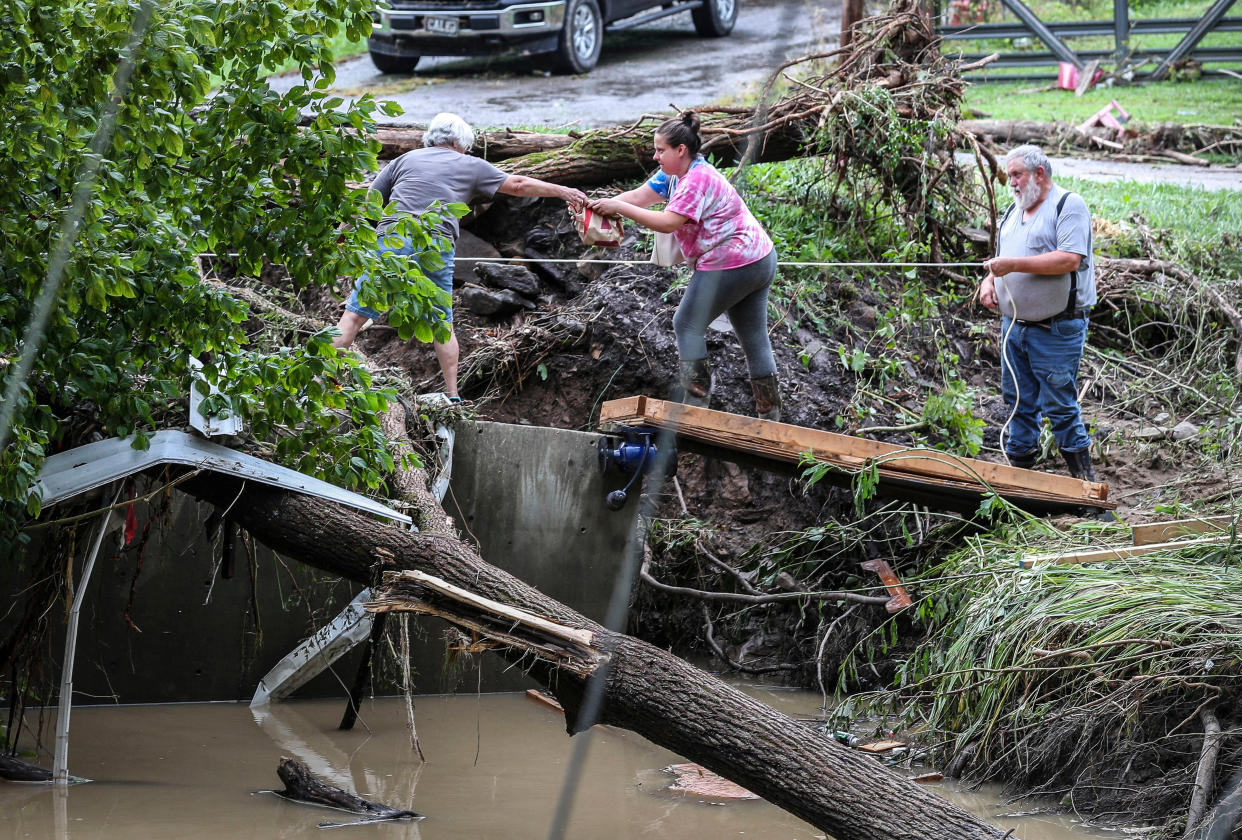 Tonya Smith, whose trailer was washed away by flooding, reaches for food from her mother, Ollie Jean Johnson, to give to Smith's father, Paul Johnson, as they use a rope to hang on over a swollen Grapevine Creek in Perry County, Ky., on Thursday.