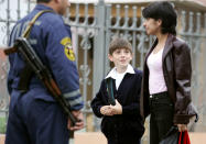 A schoolboy and his mother pass by an armed security guard as they arrive for the first lesson at a new school No.1 in the Russian town of Beslan. A schoolboy and his mother pass by an armed security guard as they arrive for the first lesson at a new school No.1 in the Russian town of Beslan, September 5, 2005. Residents of Beslan blaming authorities and still seething with anger, grieved silently on Saturday to mark the day a year ago when hundreds of their children were killed in a school siege. REUTERS/Sergei Karpukhin