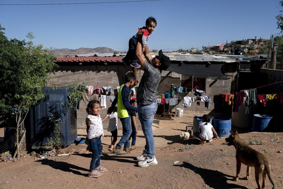 Rafael Delgado (center) holds up his baby Liam Delgado Garcia, 1, outside their home on the outskirts of Nogales on May 23, 2022. Rafael moved to Nogales to apply for asylum after his brother Carlos was kidnaped by the cartel for four days. A federal judge in Louisiana ruled that Title 42, a Trump administration era public health order, must stay in place; making it difficult for migrants in Mexico to seek asylum to the U.S.