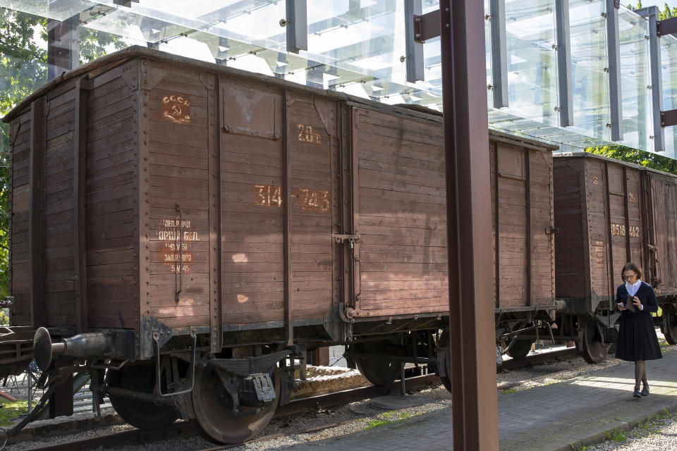 A woman passes old wagons at the Naujoji Vilnia railway station in Vilnius, Lithuania, Monday, June 14, 2021, as Lithuania marked the mass deportation 80 years ago by the Soviet Union that was occupying the Baltic nation. Deportation started on June 14, 1941, where some 280,000 people were deported to Siberian gulags, a year after Soviet troops had occupied Lithuania. (AP Photo/Mindaugas Kulbis)