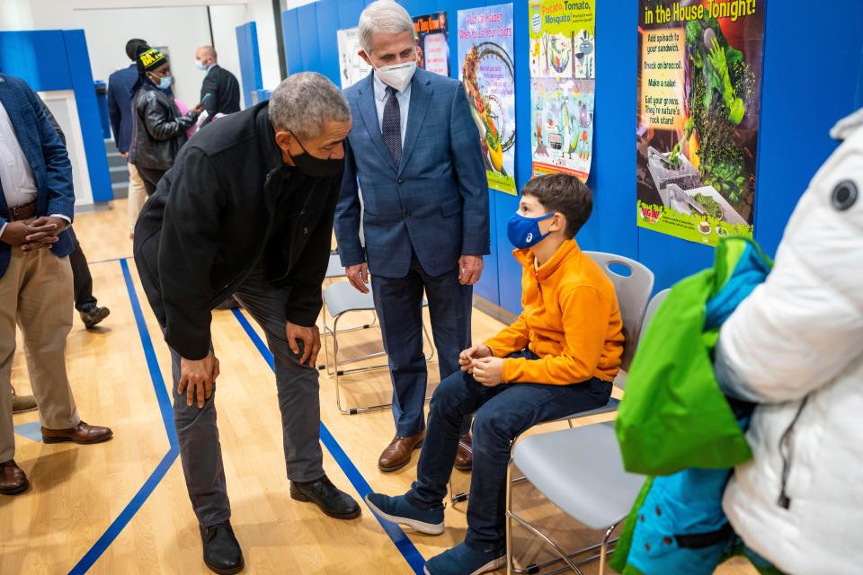 Former President Barack Obama and Dr. Anthony Fauci talk with an elementary school student preparing to get his second vaccine shot at Kimball Elementary School.