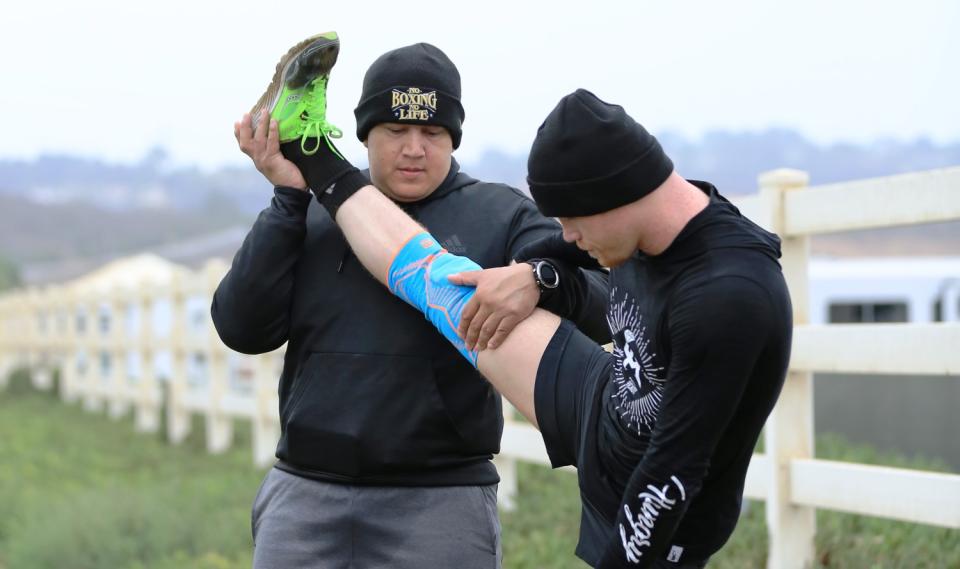 Eddy Reynoso, left, helps boxer Canelo Álvarez stretch at his training facility in San Diego.