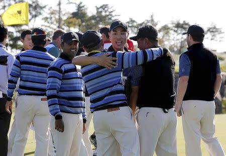 International team member Bae Sang-moon (3rd R) of South Korea celebrates with his team captain Nick Price (4th R) and vice captain K.J. Choi (2nd R) after sinking his putt to defeat U.S. team member Rickie Fowler and Jimmy Walker on the 18th hole during the four ball matches of the 2015 Presidents Cup golf tournament at the Jack Nicklaus Golf Club in Incheon, South Korea, October 9, 2015. REUTERS/Toru Hanai