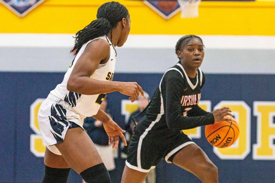 Ursuline freshman Jezelle Banks (right) drives against Sanford senior Tyler Edwards during the Warriors' 81-76 overtime win on Feb. 15 at Sanford.