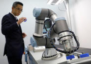 A Universal Robots employee demonstrates how a model of their industrial robot arms works in Singapore March 3, 2017. Picture taken March 3, 2017. REUTERS/Edgar Su