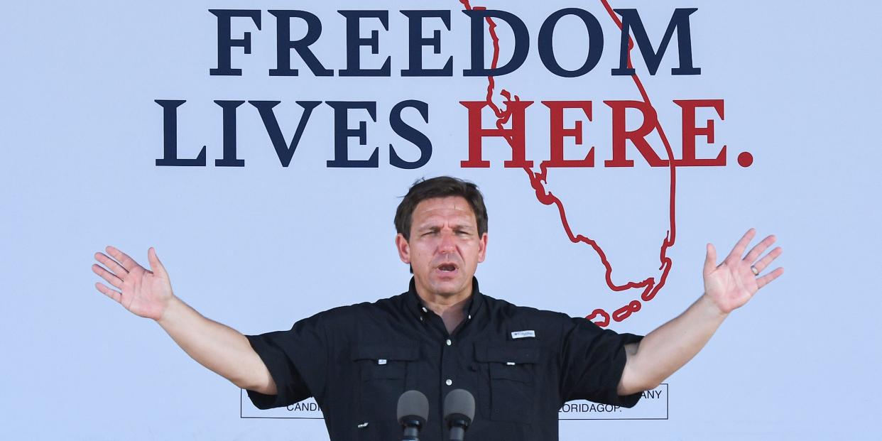 Ron DeSantis raises his arms with a map of Florida behind him