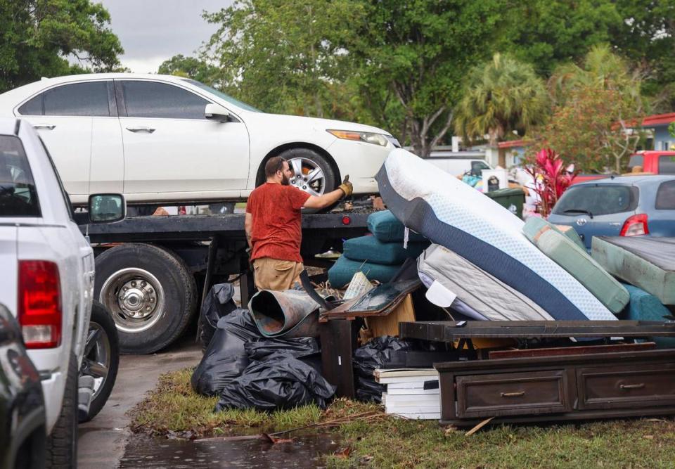 Neighbors discard damaged items in a pile on the street. A tow-truck operator gives a thumbs up as one of many damaged cars is towed away on Monday, April 17, 2023. Carl Juste/cjuste@miamiherald.com