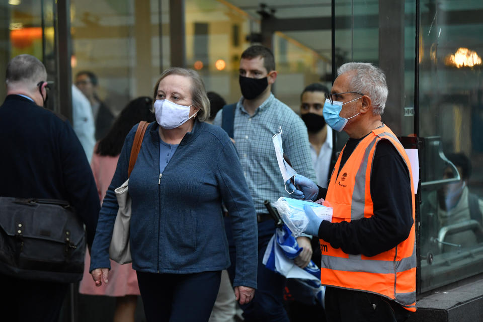 NSW Transport workers hand out face masks at Town Hall train station in Sydney.