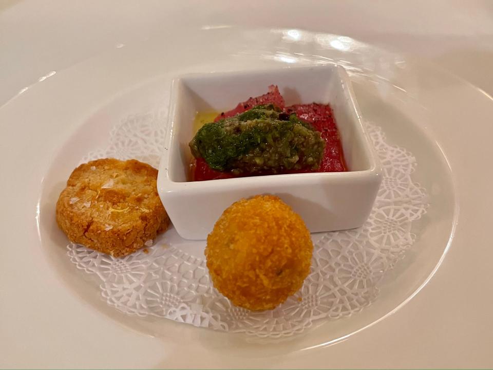 Plate of appetizers including shortbread with Parmesan and lemon zest, fried zucchini balls, and fresh sliced tuna with herb oil and salt.