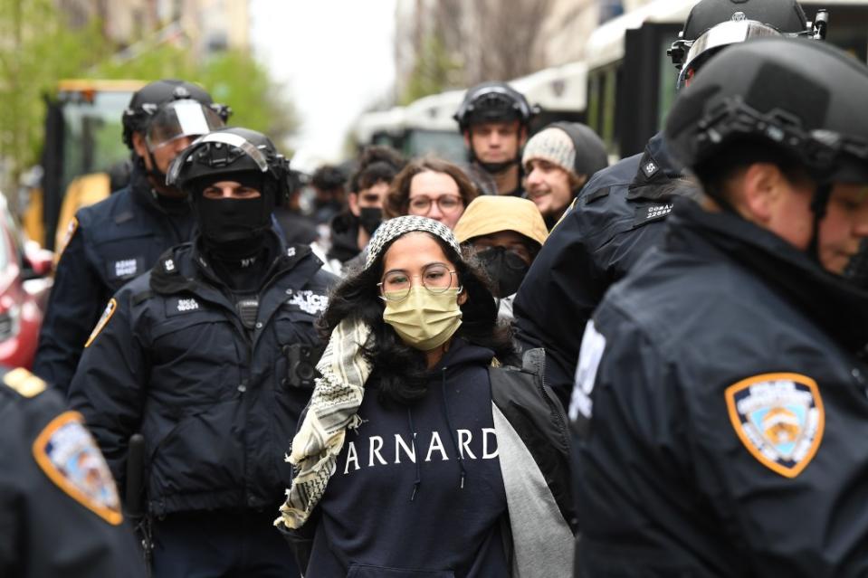 A pro-Palestinian protester wearing a face mask in handcuffs being led onto an NYPD bus. Matthew McDermott