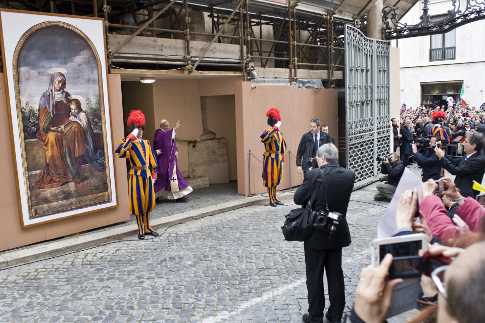 Pope Francis greets faithful at the Vatican, Sunday, March 17, 2013. Pope Francis began his first Sunday as pontiff by making an impromptu appearance to the public from a side gate of the Vatican, startling passersby and prompting cheers, then kept up his simple, spontaneous style by delivering a brief, off-the-cuff homily at the Vatican's tiny parish church. Dressed only in white cassock, Francis waved to the crowd in the street outside St. Anna's Gate and before entering the church, which serves Vatican City State's hundreds of residents, he shook hands of the parishioners and kissed babies. (AP Photo/Antonello Nusca)