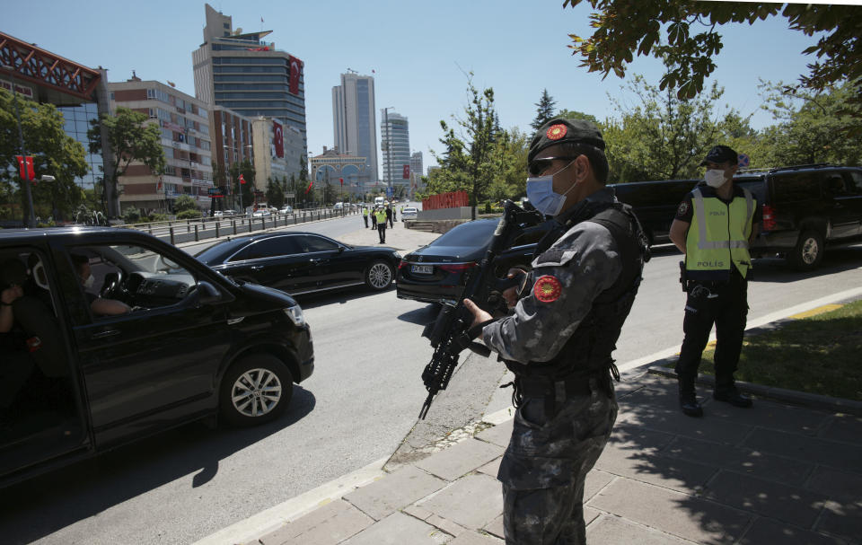 Security officers stand guard as the car carrying Turkey's President Recep Tayyip Erdogan drives in a motorcade to the parliament to attend a ceremony in the capital Ankara, Turkey, Thursday, July 15, 2021. Turkey on Thursday marked the fifth anniversary of a failed coup attempt against the government, with a series of events commemorating victims who died trying to quash the uprising. (AP Photo/Burhan Ozbilici)