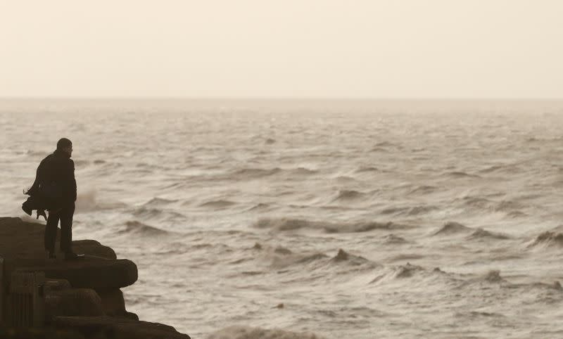 FILE PHOTO: A man looks out over the Irish sea off Blackpool, England