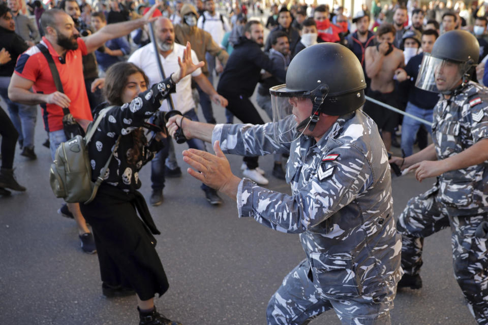 Anti-government protesters clash with riot police on a road leading to the parliament building in downtown Beirut, Lebanon, Tuesday, Nov. 19, 2019. Scuffles have broken out in central Beirut as hundreds of anti-government protesters tried to prevent lawmakers from reaching Parliament. (AP Photo/Hassan Ammar)