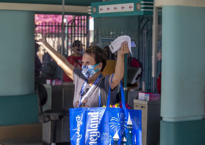 ANAHEIM, CA - March 18: After being shut down for over a year due to the Coronavirus pandemic, a Disney fan throws up her arms with excitement as she passes through the front gate to attend the debut of Disney California Adventure's "A Touch of Disney" food event at Disney California Adventure Park Thursday, March 18, 2021 in Anaheim, CA. This spans the entire DCA park and allows guests to eat, interact with characters and explore the grounds. A Touch of Disney, the new limited-time ticketed experience at Disney California Adventure Park which has sold out, takes place March 18 through April 19, 2021. (Allen J. Schaben / Los Angeles Times)