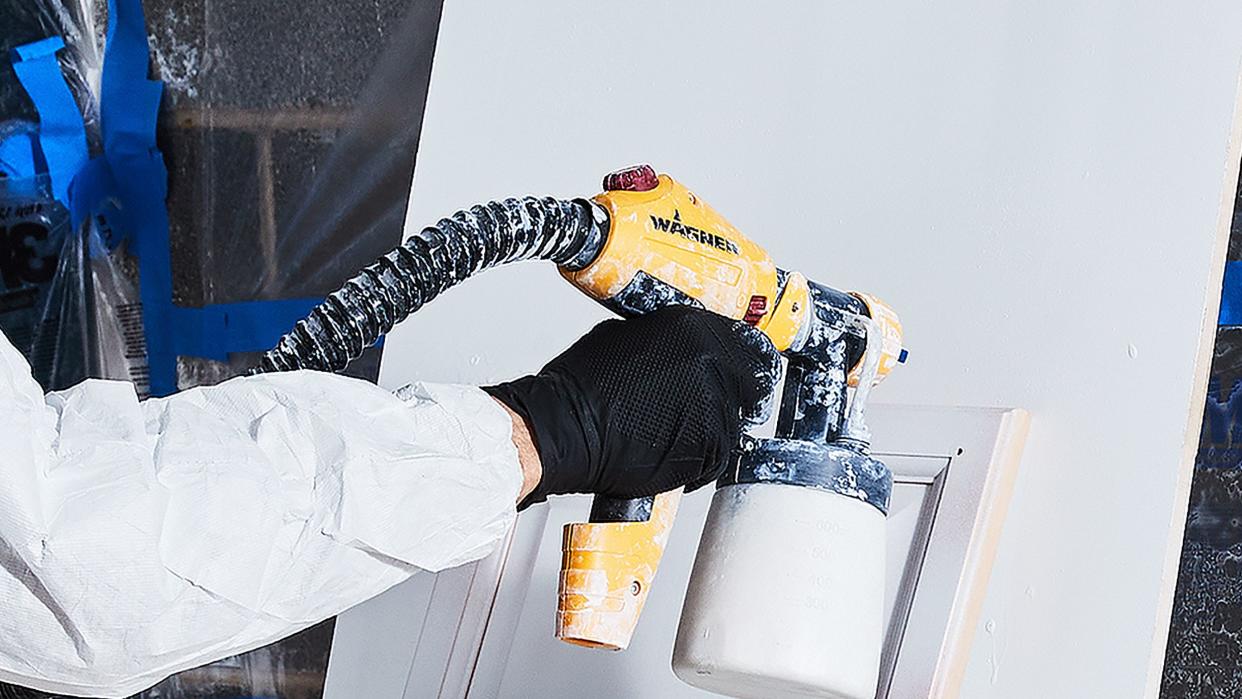 a person spray painting kitchen cabinets