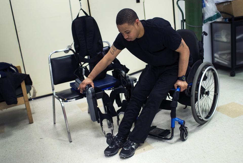 Samuels lifts himself from his wheelchair into a ReWalk electric powered exoskeletal suit for a therapy session at the Mount Sinai Medical Center in New York City