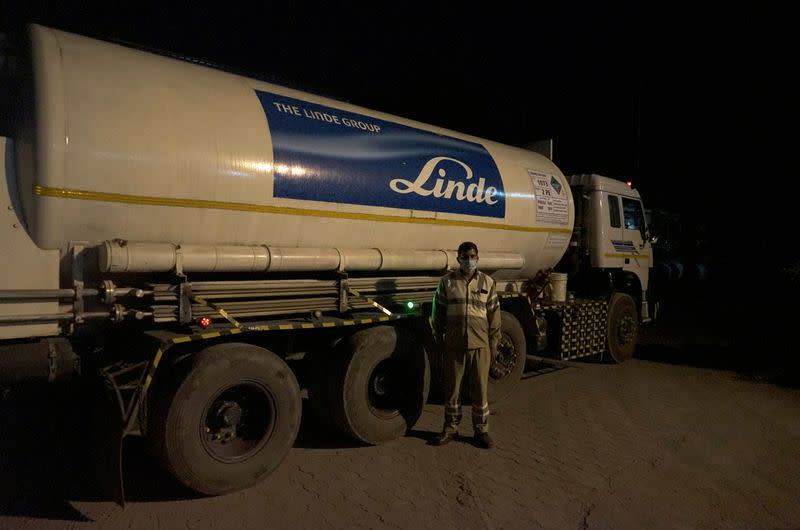 Subhas Kumar Yadav poses in front of a tanker carrying liquid oxygen along a road in Selaqui