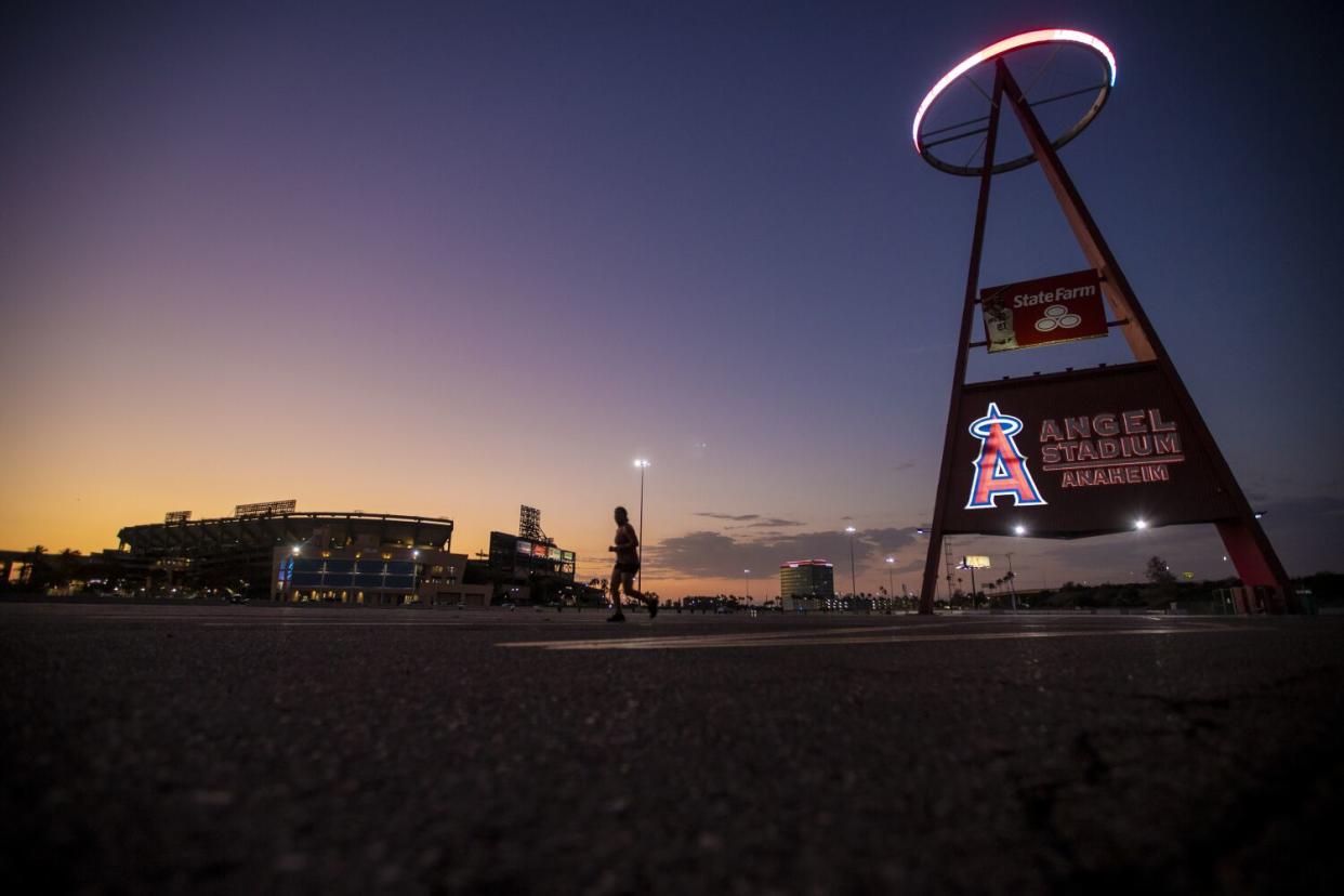 A runner passes by as the sun sets behind Angel Stadium.