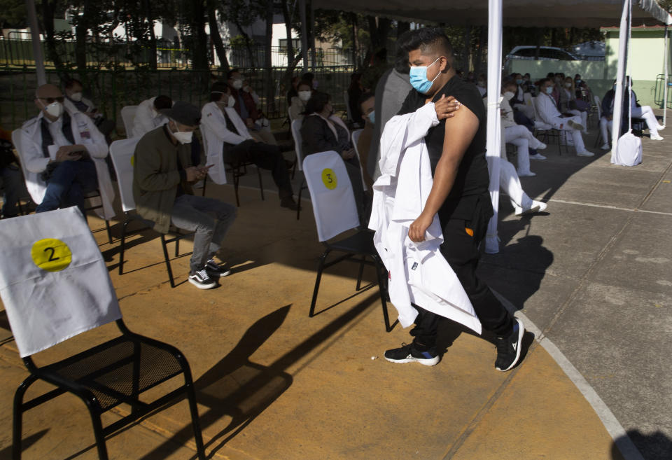 A health worker holds his arm where he was given a shot of the Pfizer-BioNTech vaccine for COVID-19 as he arrives to sit in an observation area at the N-1 military base in Mexico City, Wednesday, Dec. 30, 2020. (AP Photo/Marco Ugarte)