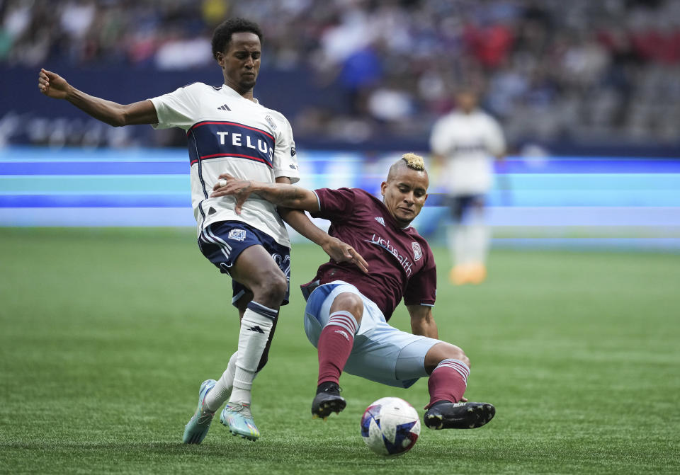 Vancouver Whitecaps' Ali Ahmed, left, and Colorado Rapids' Michael Barrios vie for the ball during the first half of an MLS soccer match Saturday, April 29, 2023, in Vancouver, British Columbia. (Darryl Dyck/The Canadian Press via AP)