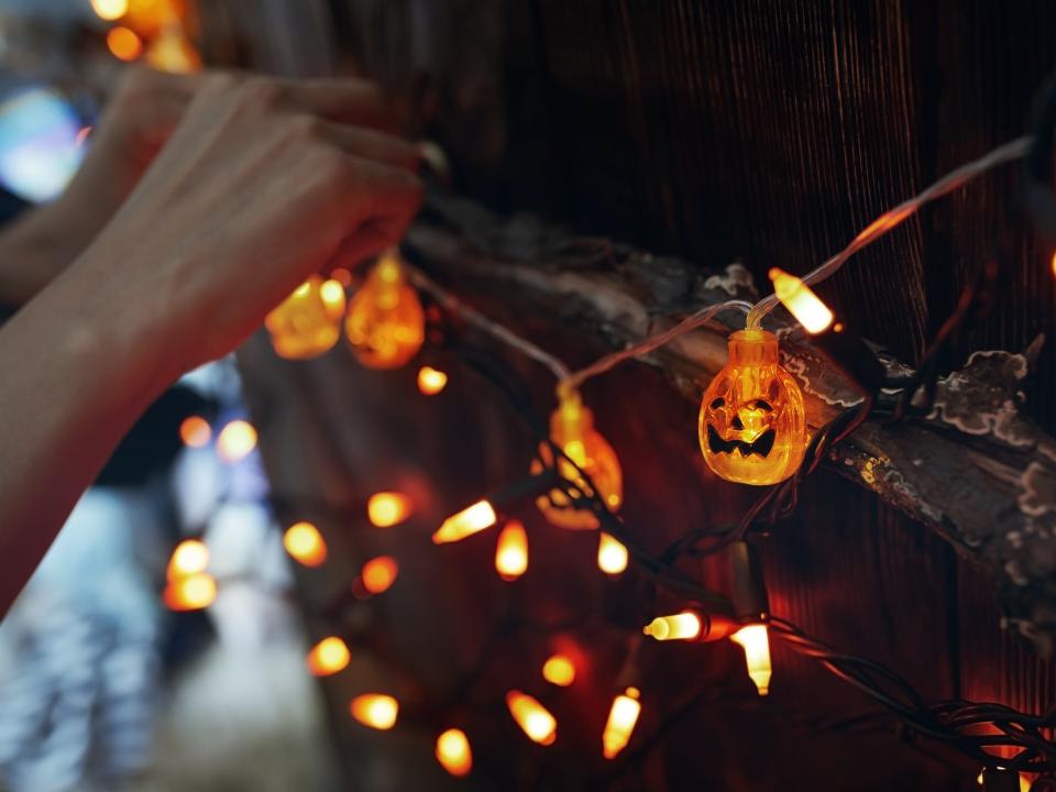 Woman hanging decorative eletric lights with pumpkins