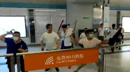 Social media video grab of men in white t-shirts and face masks attacking anti-extradition bill demonstrators and reporters at a train station in Hong Kong