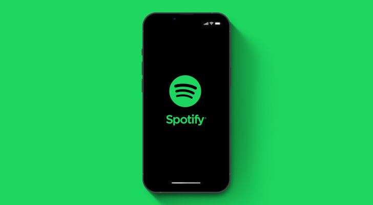 Spotify (SPOT) app on smartphone iPhone 13 Pro screen on green background.