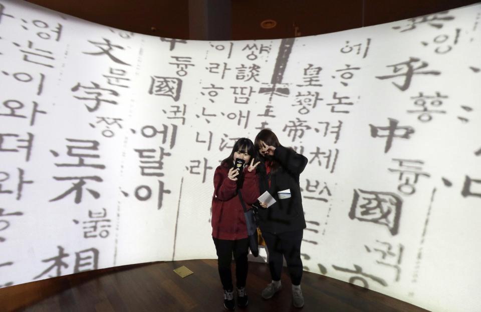 In this Wednesday, Dec. 28 photo, high school students take a selfie in front of a screen showing Korean traditional characters at the National Hangeul Museum in Seoul, South Korea. Impeached President Park Geun-hye's surname is "Park," right? Nope. In Korean it's closer to "Bahk." Park's allegedly corrupt confidante, Choi Soon-sil, pronounces her name more like "Chwey" than the way it's rendered in English. There is a gulf, often a wide one, between the way Koreans write their names in English and the way they actually sound. (AP Photo/Ahn Young-joon)