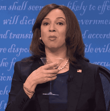 Maya Rudolph imitates Kamala Harris with a drink, expresses herself with hand gestures and wears a suit and pearls