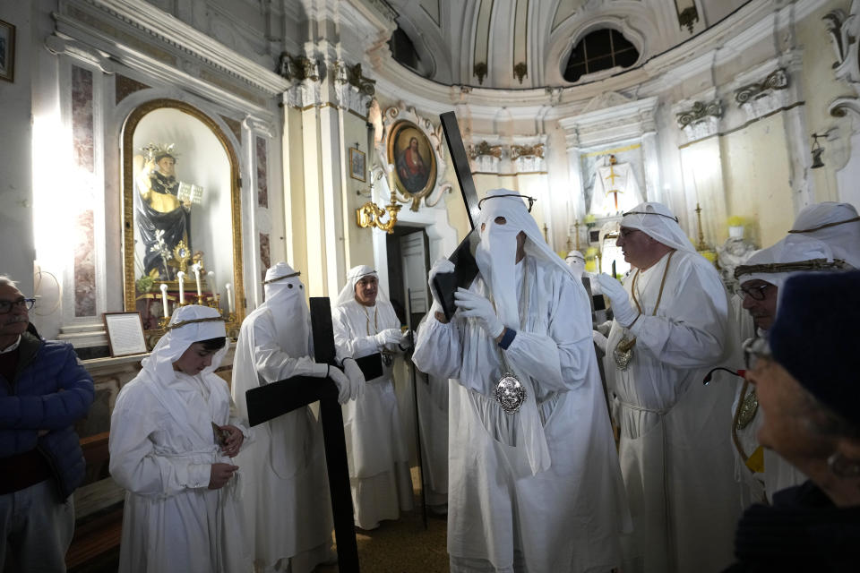 Members of a confraternity carry crosses and pray in the San Vincenzo church during a Holy Thursday procession the in Procida iIland, Italy, Thursday, March 28, 2024. Italy is known for the religious processions that take over towns big and small when Catholic feast days are celebrated throughout the year. But even in a country where public displays of popular piety are a centuries-old tradition, Procida's Holy Week commemorations stand out.( AP Photo/Alessandra Tarantino)