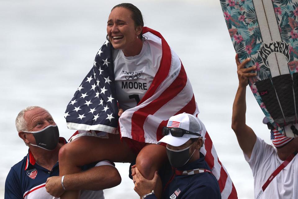 <p>Team USA's Carissa Moore wraps herself in the American flag after winning the women's Surfing gold medal final at Tsurigasaki Surfing Beach July 27.</p>