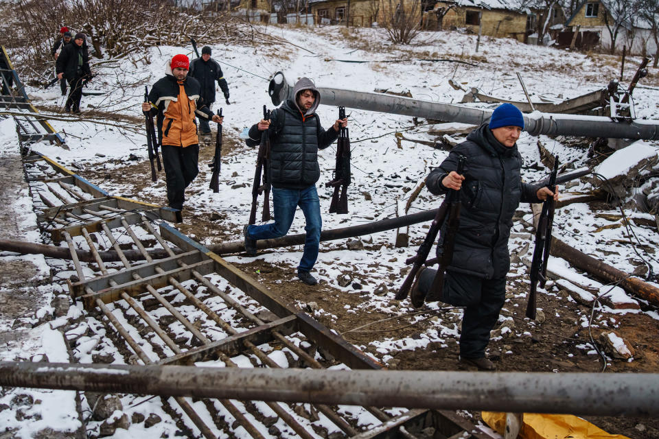 Volunteer fighters transport rifles across a river under a destroyed bridge to reinforce Ukrainian troops in Irpin on March 1.<span class="copyright">Marcus Yam—Los Angeles Times/Getty Images</span>