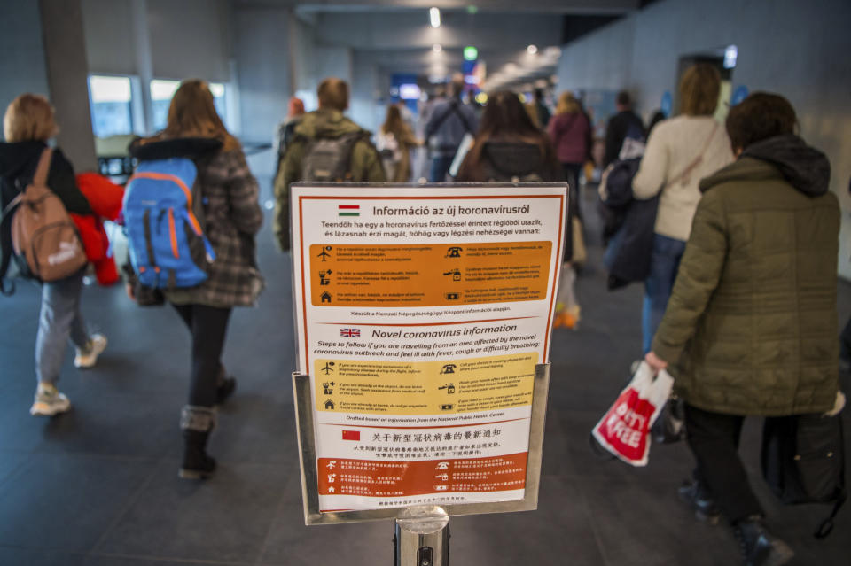 People pass by a notice as precautionary measures against the spreading of novel coronavirus, at Budapest Liszt Ferenc International Airport in Budapest, Hungary, Wednesday, Feb. 5, 2020. So far almost 900 passenger arriving directly from China have been examined at the airport. (Zoltan Balogh/MTI via AP)