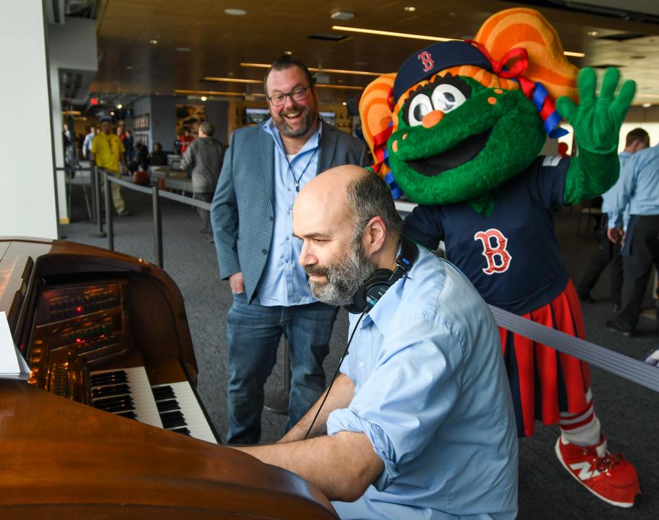 Fenway Park organist Josh Kantor plays on the new Polar Park organ on Opening Day this season. Local pianist Dave O’Brien, left, observes as Red Sox mascot Tessie walks by and waves.