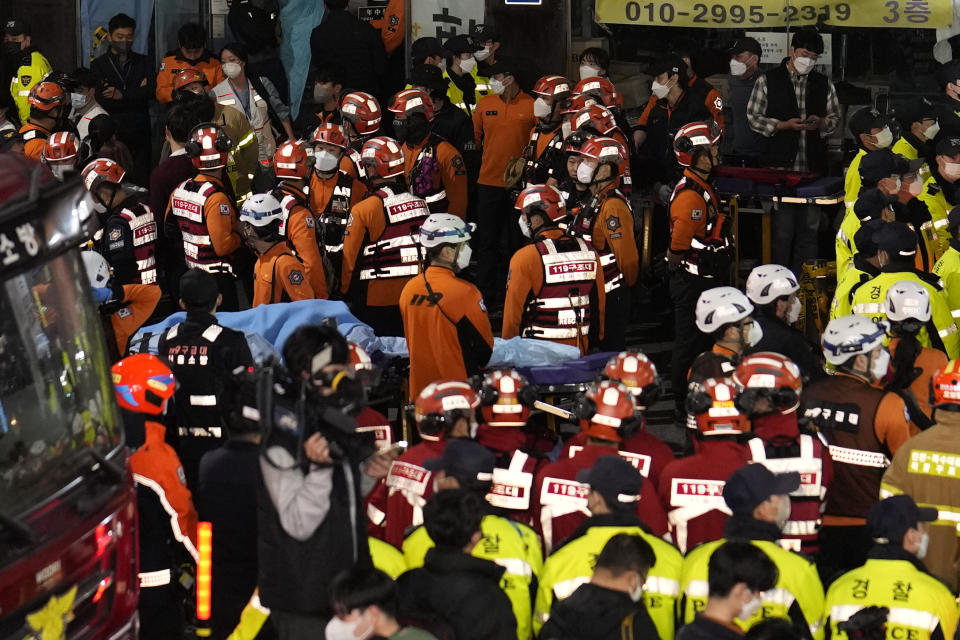 Rescue workers, firefighters and police officers are seen on the street near the scene in Seoul, South Korea, Sunday, Oct. 30, 2022. Scores of people were killed and others were injured as they were crushed by a large crowd pushing forward on a narrow street during Halloween festivities in the capital, South Korean officials said. (AP Photo/Lee Jin-man)