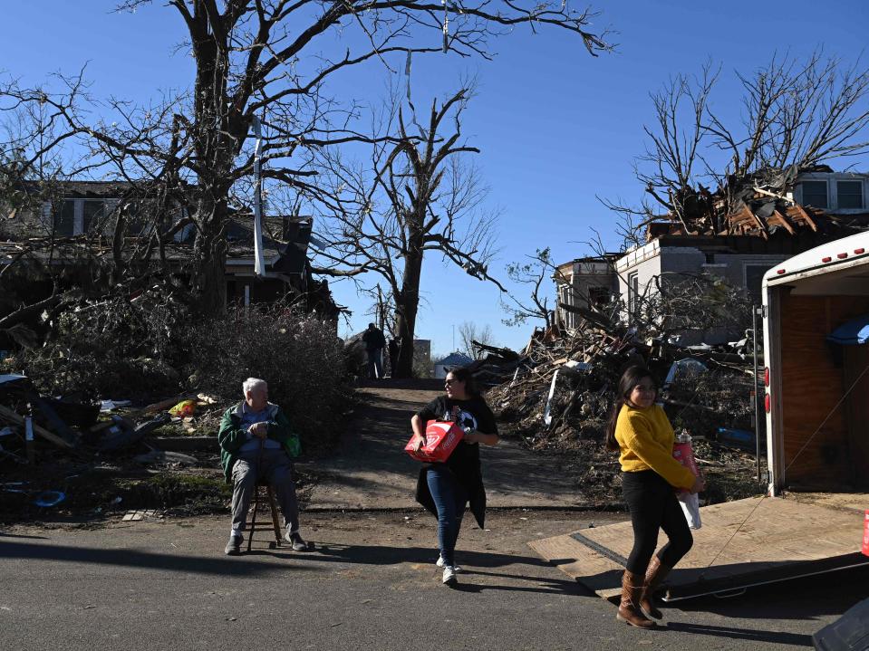 William Richards (L) sits near his sons home as families pass out food in a neighborhood impacted by a tornado after extreme weather hit the region December 12, 2021, in Mayfield, Kentucky (AFP via Getty Images)