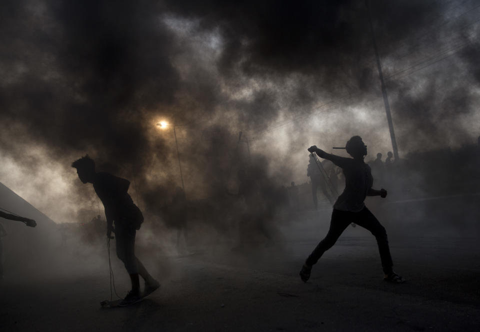 Palestinian protesters hurl stones during a demonstration at the entrance of Erez border crossing between Gaza and Israel, in the northern Gaza Strip, Wednesday, Oct. 3, 2018. (AP Photo/Khalil Hamra)