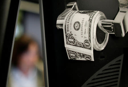 FILE PHOTO: A magazine cut-out of a toilet roll made up of paper money, is taped to a screen of a trading terminal at the German stock exchange in Frankfurt, June 3, 2009. REUTERS/Kai Pfaffenbach/File Photo