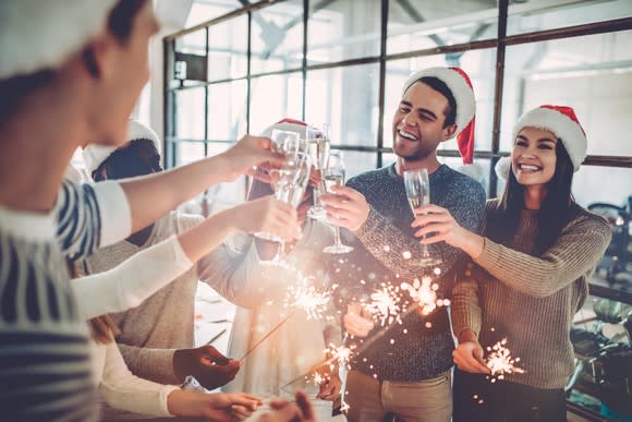 People wearing Santa hats celebrate in an office.