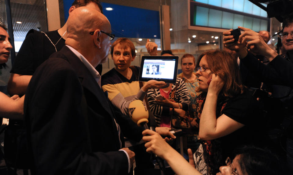 A journalist shows a picture of Edward Snowden to airline passenger at the arrival gate of the Sheremetyevo International Airport in Moscow. (Photo: Asily Maximov/AFP/Getty Images)