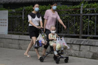Residents carry their fresh produces after shopping in Beijing, Monday, Aug. 15, 2022. China’s central bank trimmed a key interest rate Monday to shore up sagging economic growth at a politically sensitive time when President Xi Jinping is believed to be trying to extend his hold on power. (AP Photo/Ng Han Guan)