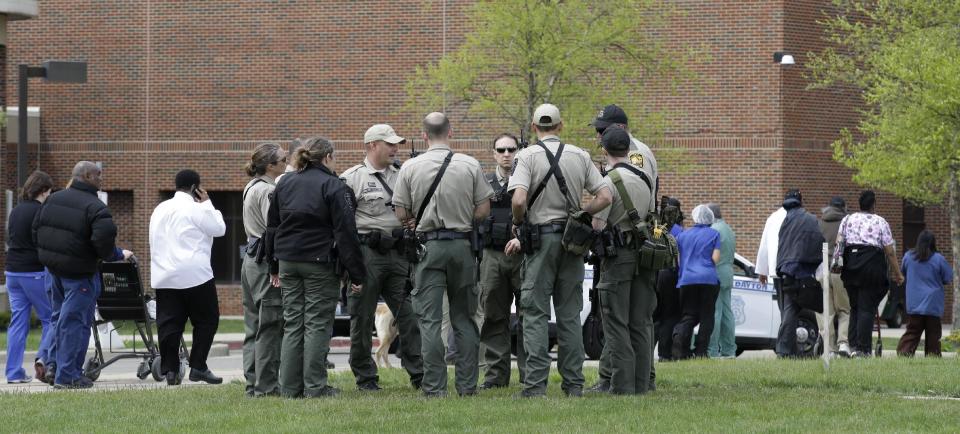 Police officials gather outside a Veterans Affairs hospital after people who were evacuated were told they could reenter the building, Monday, May 5, 2014, in Dayton, Ohio. A city official says a suspect is in police custody after a shooting at the hospital that left one person with a minor injury. (AP Photo/Al Behrman)