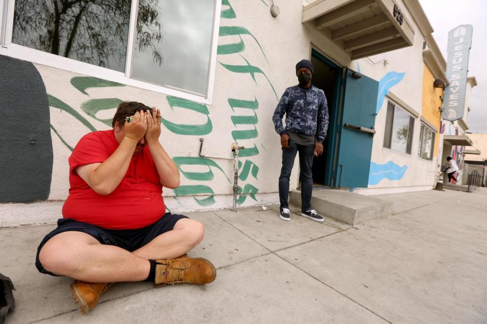 Andrew Truelove puts his hands over his face while sitting in front of the Beacon Light Mission in Wilmington.