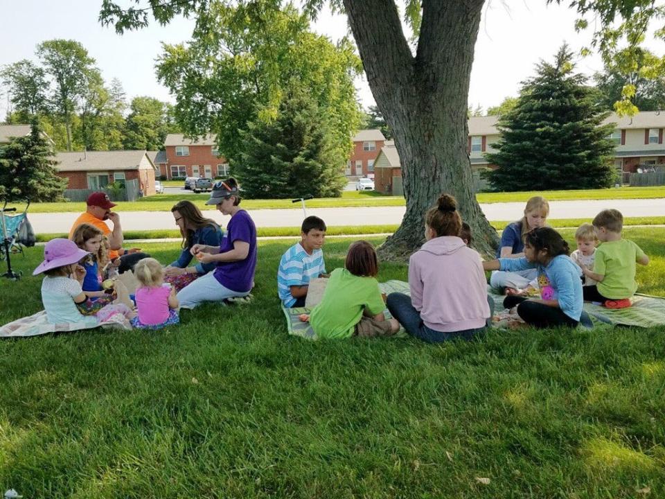Kids and their families share a meal in the shade as part of the summer food service program a couple years ago in Bloomington. The program will be offered again this summer and begins May 22.