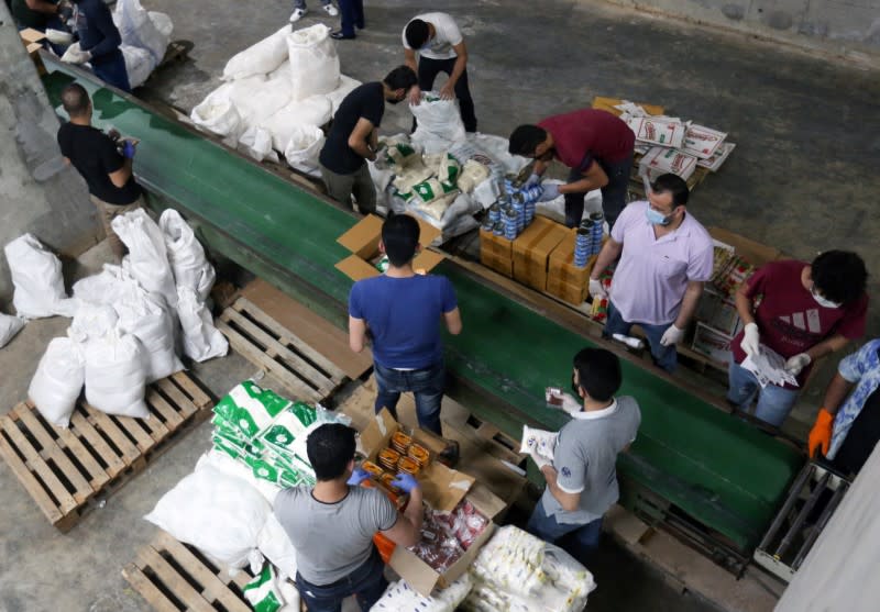 Volunteers wearing protective masks and gloves sort boxes with food for distribution to people in need, in Beirut