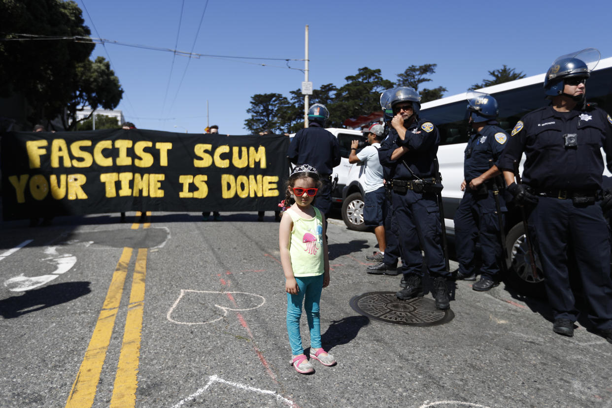 A child stands next to a line of police officers by San Francisco's Alamo Square as demonstrators rally ahead of a news conference by the organizers of the canceled rally on Aug. 26, 2017. (Photo: Stephen Lam via Getty Images)