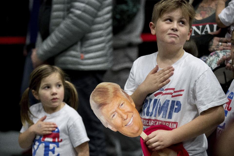 Children in the audience stand for the pledge of allegiance before President-elect Donald Trump takes the stage at a rally at DeltaPlex Arena, Friday, Dec. 9, 2016, in Grand Rapids, Mich. (AP Photo/Andrew Harnik)