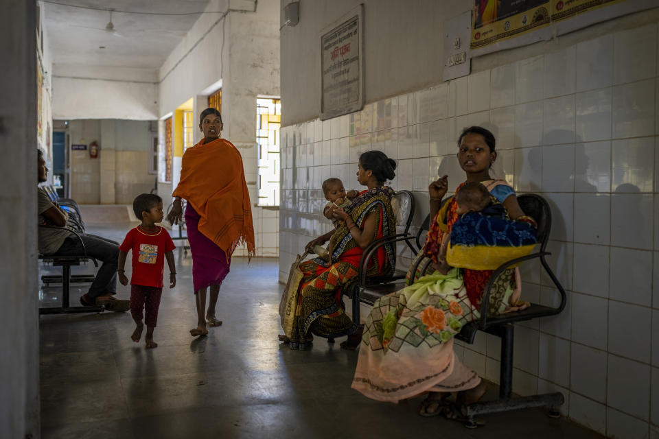 Phagni Poyam, 23, centre right, sits on a bench as she waits for her turn to get checked up at a hospital in Orchha in central India's Chhattisgarh state, Nov. 15, 2022. These ambulances, first deployed in 2014, reach inaccessible villages to bring pregnant women to an early referral center, a building close to the hospital where expectant mothers can stay under observation, routinely visit doctors if needed until they give birth. Since then the number of babies born in hospitals has doubled to a yearly average of about 162 births each year, from just 76 in 2014. The state has one of the highest rates of pregnancy-related deaths for mothers in India, about 1.5 times the national average, with 137 pregnancy related deaths for mothers per 100,000 births. (AP Photo/Altaf Qadri)